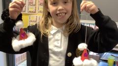 Class 3 child showing off some Santa hats that were made to sell