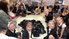Children fitting their shoes inside the template of a dinosaur footprint