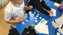Class 3 children making number cards to work out the nrich maths problem together.
