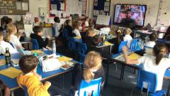 A class of children watch a video of poet Joshua Seigal on the whiteboard