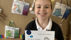 Smiling girl holds up a letter.
