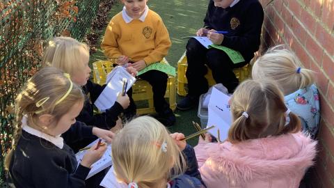 Children sitting in a garden writing in books