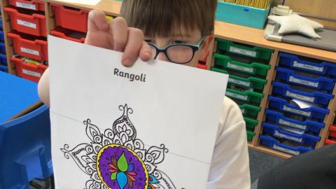 class 3 child showing off their rangoli pattern mindfulness colouring