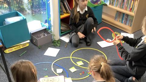 Girls using practical resources to work out their maths challenge