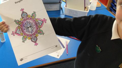 Class 3 child showing off their rangoli pattern mindfulness colouring