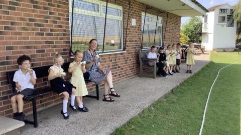 A group of children sit on benches eating ice creams