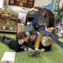 Teacher and children laying on floor reading a book