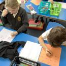 Two children work together solving division questions on coloured paper in felt tip pen