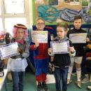 children holding up achievement awards in class